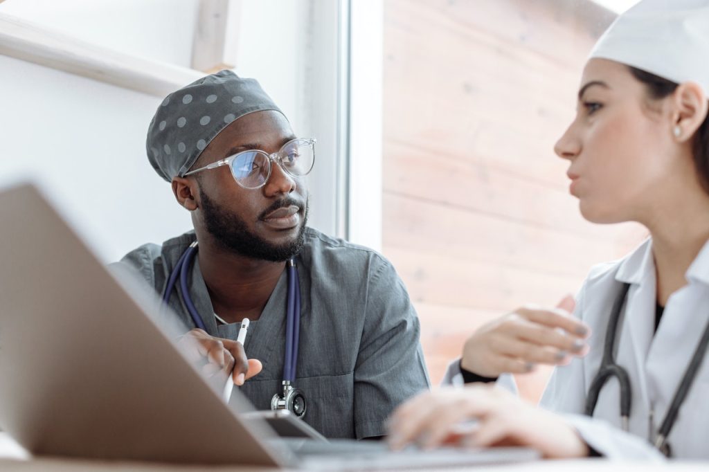 Healthcare worker in scrubs consulting with a doctor over a laptop