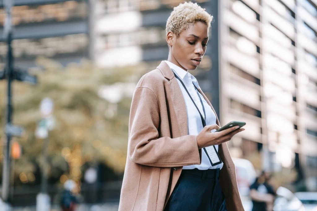Professional woman in a blazer checking her smartphone on a city street