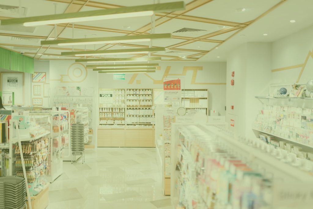 Interior of a brightly lit retail store with shelves of stationery and cards