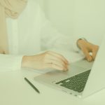 Person wearing a headscarf working on a laptop at a bright desk
